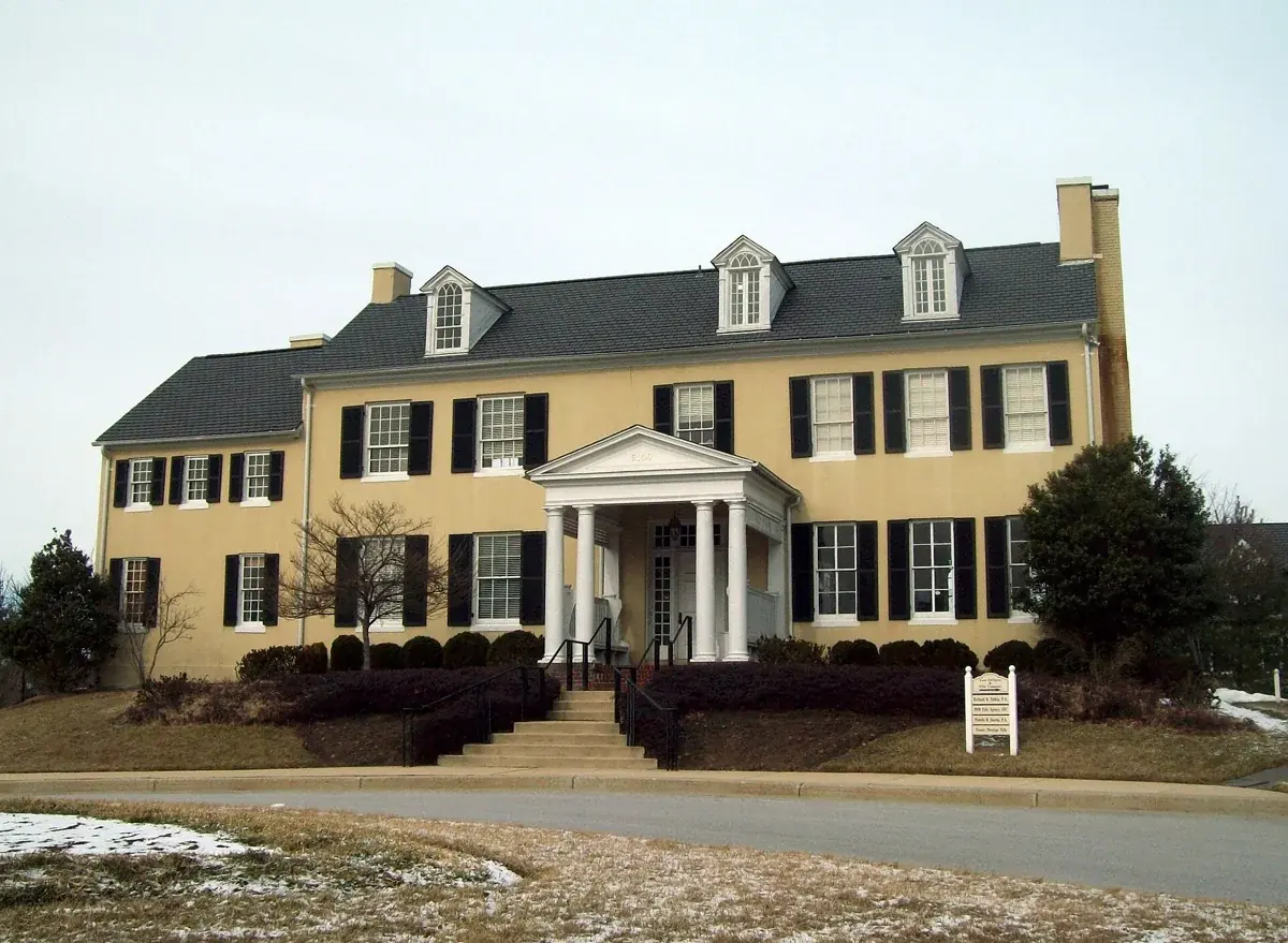 The yellow facade and white entrance porch of historic Dorsey Hall in Ellicott City, Maryland